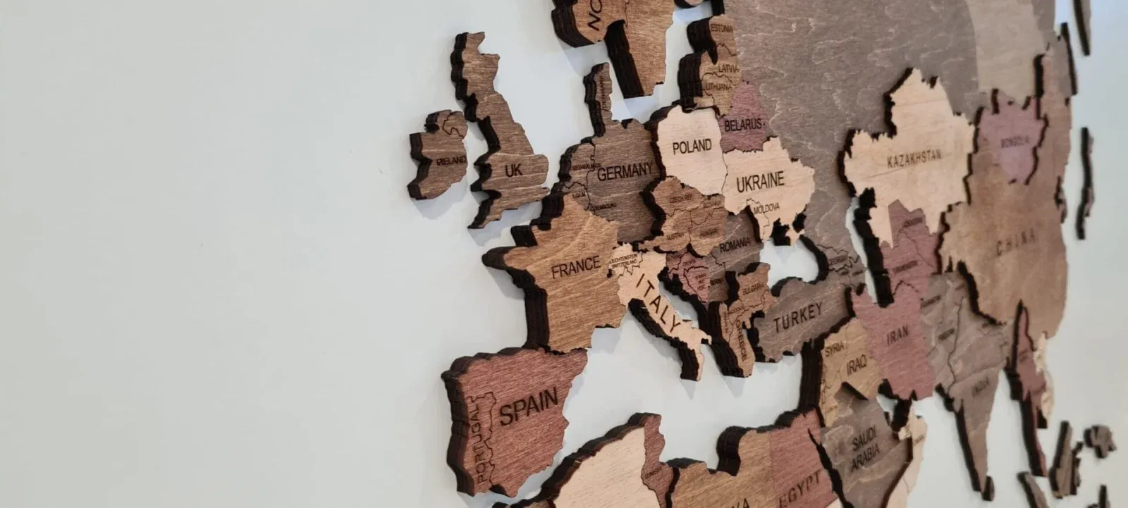 Angled close-up of a multitone Your Wooden Map across Europe showing engraved names, boundaries and layered dark edges