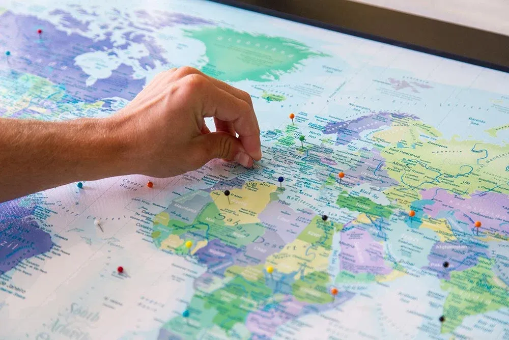 Close-up of a GeoJango framed canvas map being marked with a travel pin