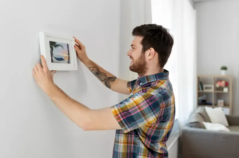 Person arranging a framed photograph on a wall