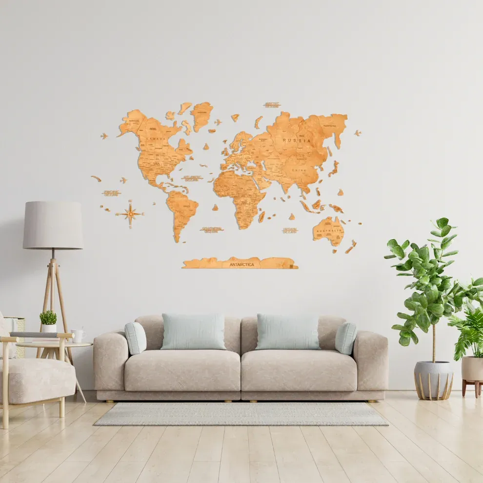 Light honey-brown GeoArte wooden world map installed above a neutral sofa in a bright living room