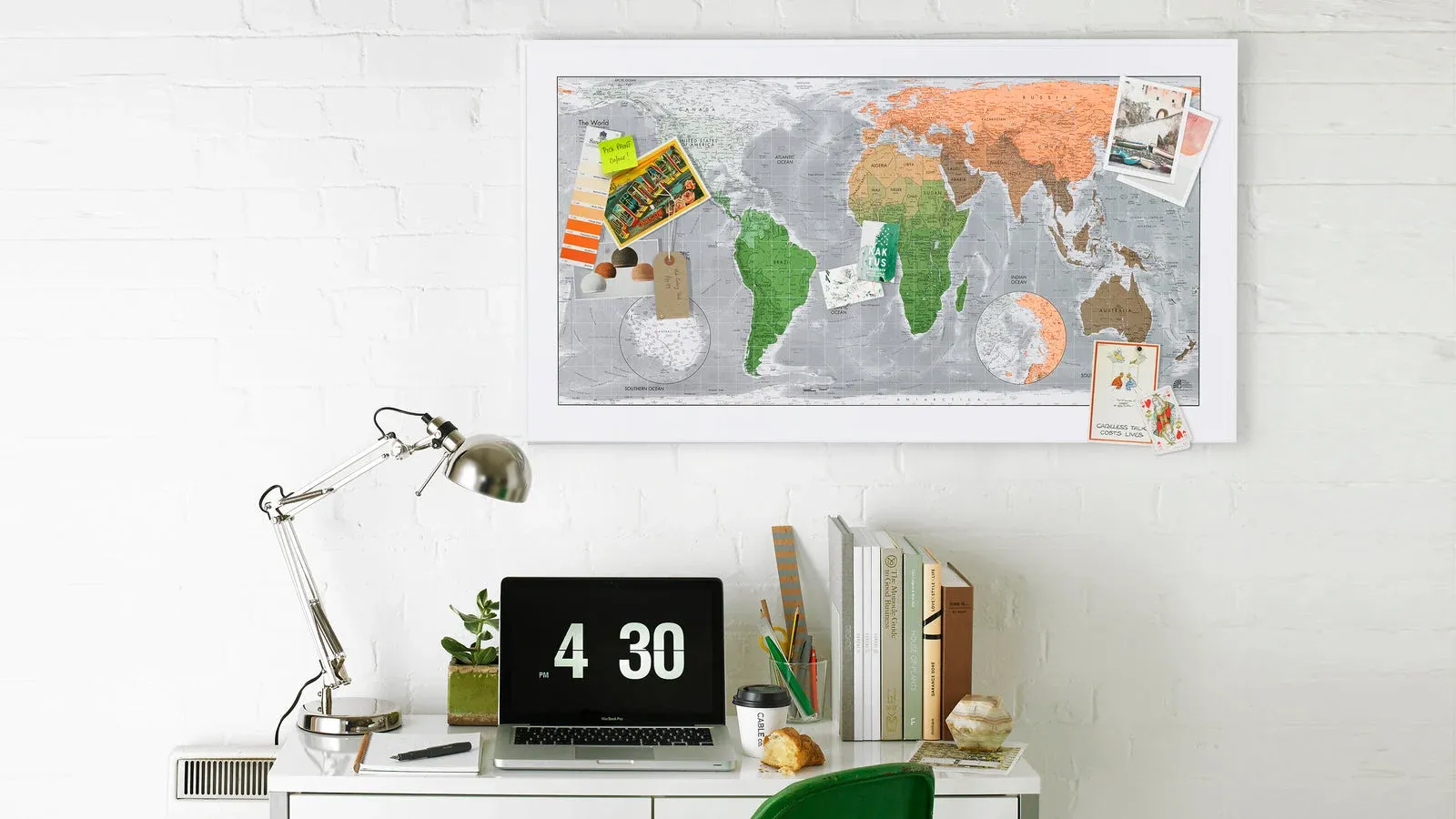 Future Maps world map holding photos and notes above a home-office desk