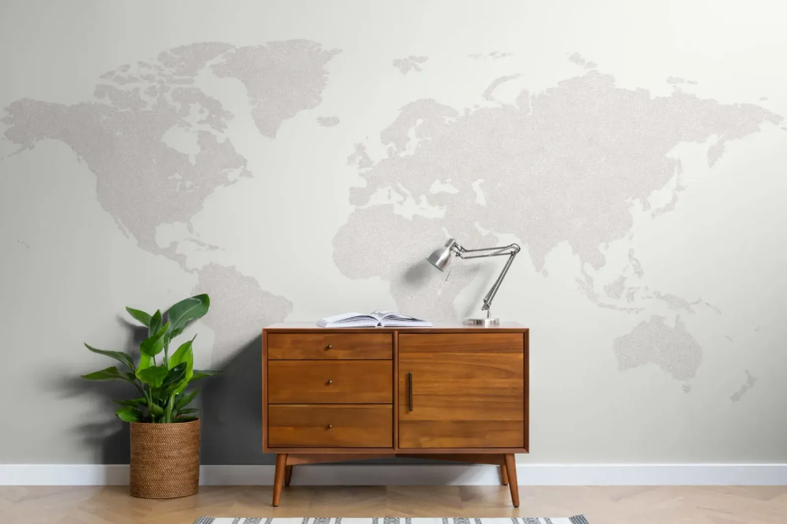 Pale world map mural covering the wall behind a wooden sideboard